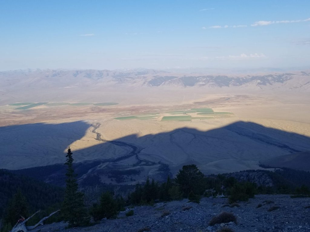 Long shadows cast into the valley from a jagged mountain in the early morning sun
