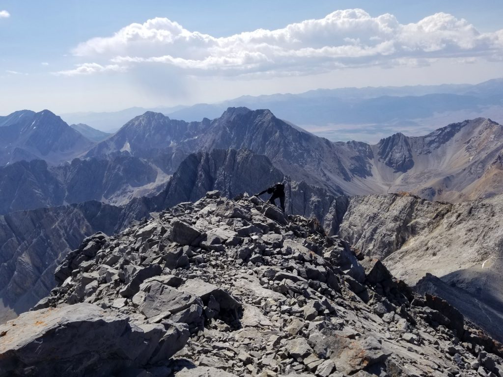 High mountain summit ridge on a partially cloudy day and mountains in the background
