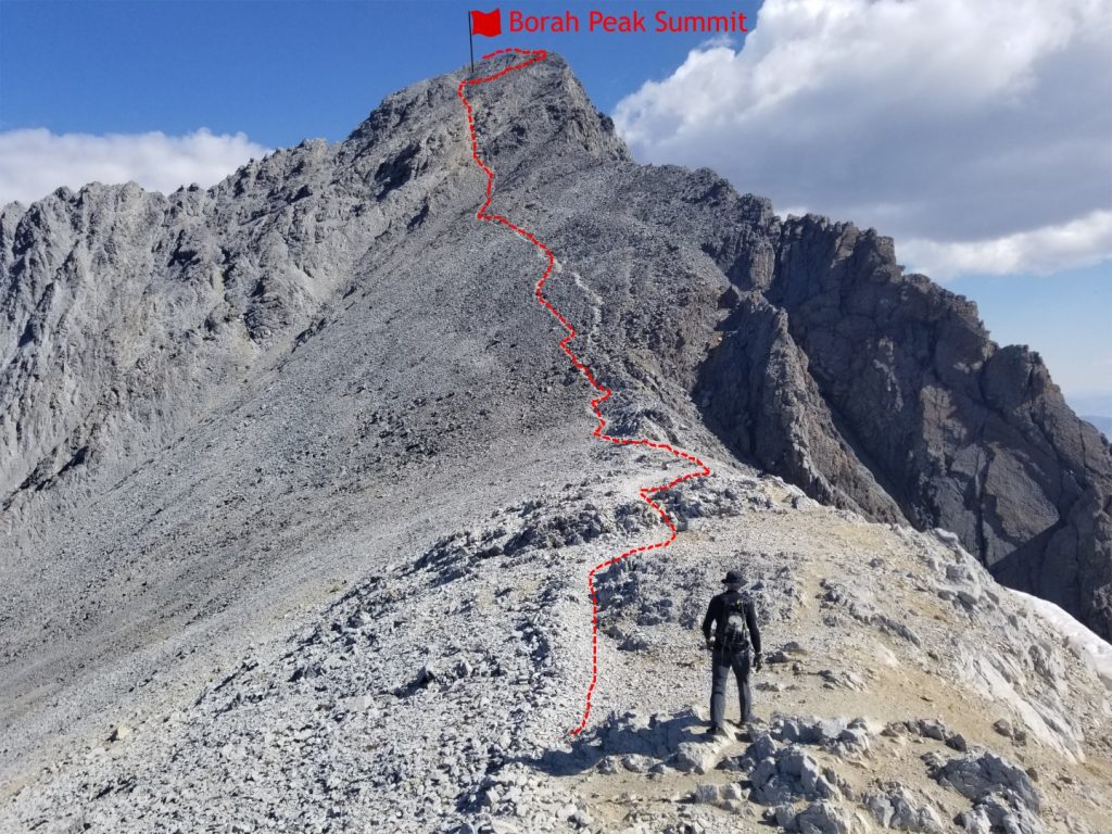 Trail going to the summit of a mountain with a hiker looking on